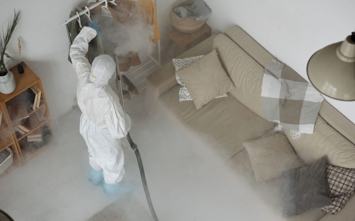 Pessoa em equipamento de proteção sanitizando interior de casa para segurança contra COVID-19