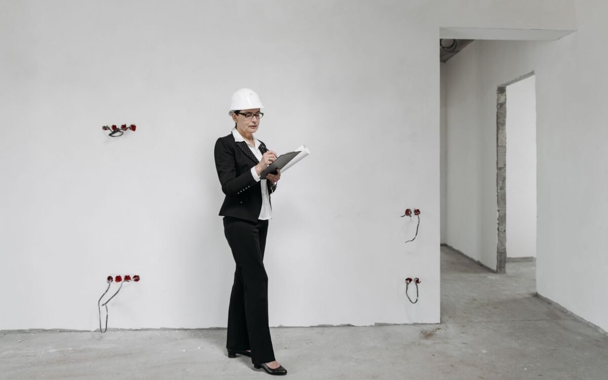Mulher de capacete revisa anotações em um canteiro de obras, examinando o progresso