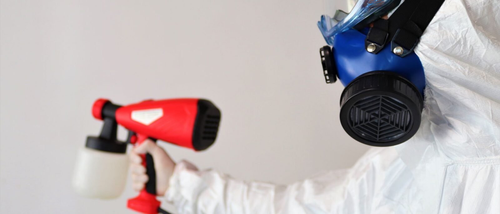 Um trabalhador em equipamento de proteção usa um spray desinfetante em ambientes fechados